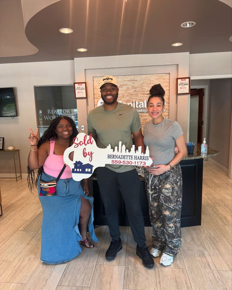 Bernadette Harris with two clients and her Sold key sign at the title company