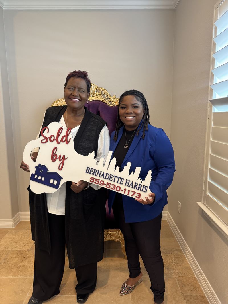 Bernadette Harris and a client holding her Sold key sign on closing day